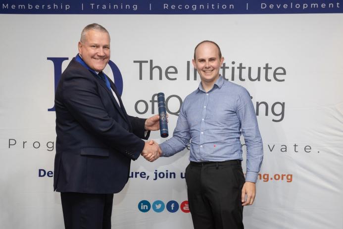 Lewis Coxon receiving his award from IQ President Viv Russell