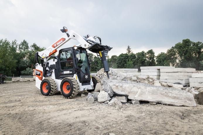 A Bobcat S86 R-series skid-steer loader with breaker attachment in a concrete demolition application