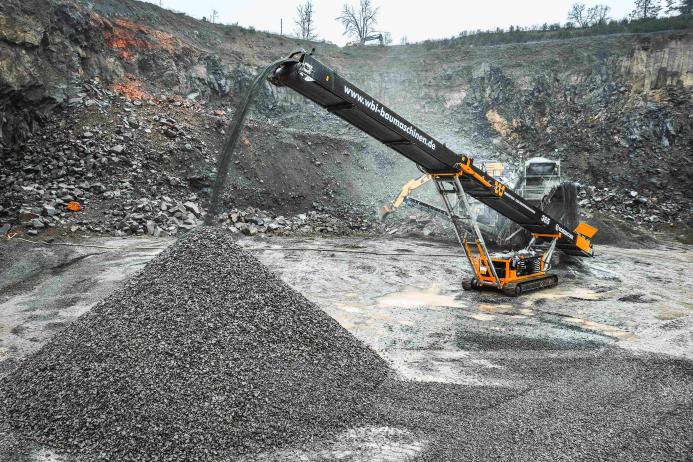 Screencore 365 stockpiler in WBI Baumaschinen livery receiving feed from a primary crusher