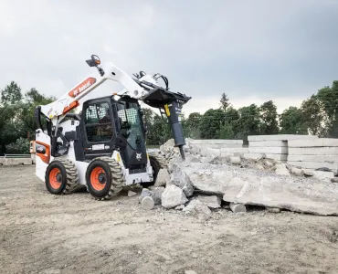 A Bobcat S86 R-series skid-steer loader with breaker attachment in a concrete demolition application