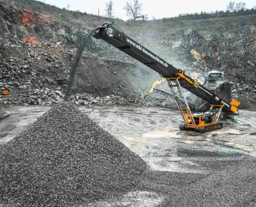 Screencore 365 stockpiler in WBI Baumaschinen livery receiving feed from a primary crusher