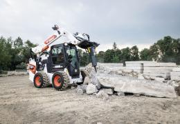A Bobcat S86 R-series skid-steer loader with breaker attachment in a concrete demolition application
