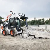 A Bobcat S86 R-series skid-steer loader with breaker attachment in a concrete demolition application