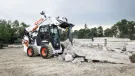 A Bobcat S86 R-series skid-steer loader with breaker attachment in a concrete demolition application